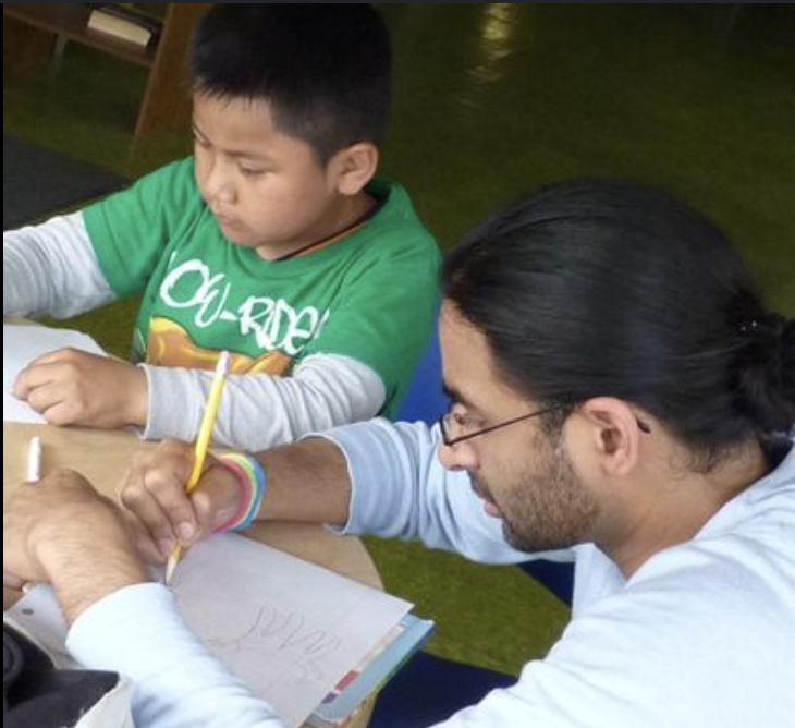 A volunteer tutor helping a young student with schoolwork at Transformations CDC